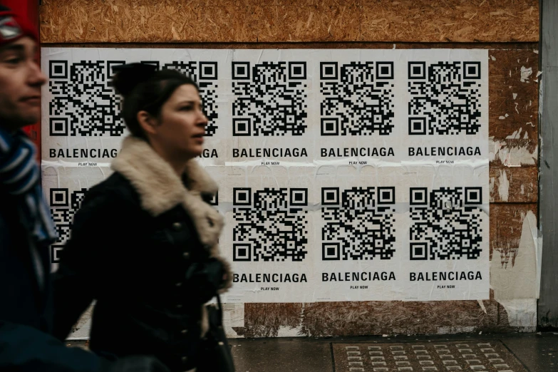 a man and woman walking by a wall with a qr code on it