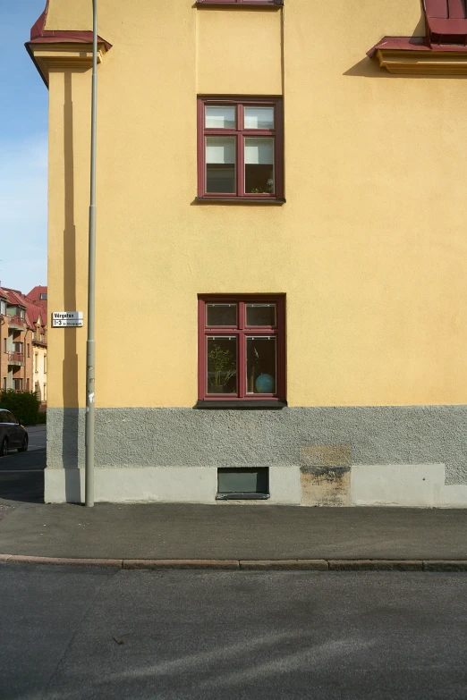 a yellow building with brown window frames and a fire hydrant