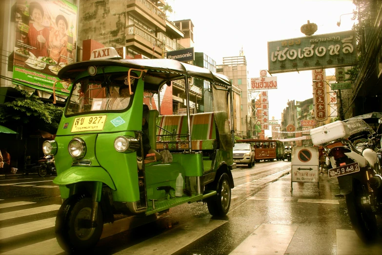 the small green vehicle is driving down the road