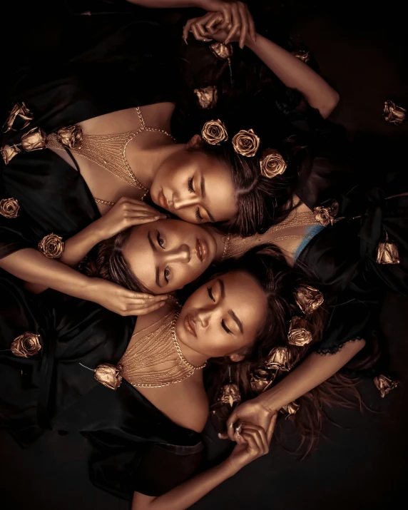three girls laying in a circle together, wearing gold jewelry