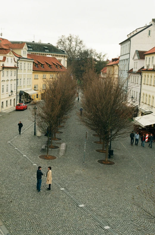 many people walk on a stone street near tall buildings