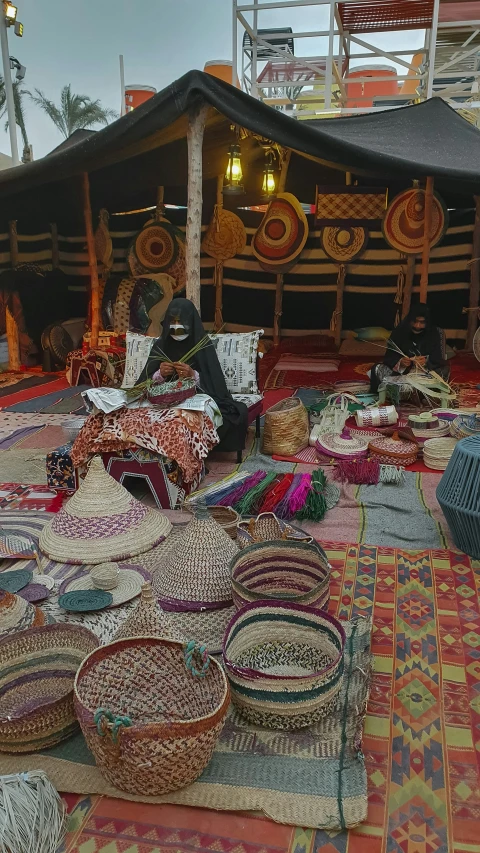 a tent covered in lots of baskets with people walking near