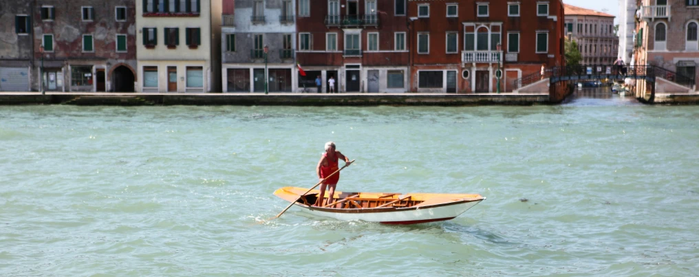 a man standing on top of a boat in a canal