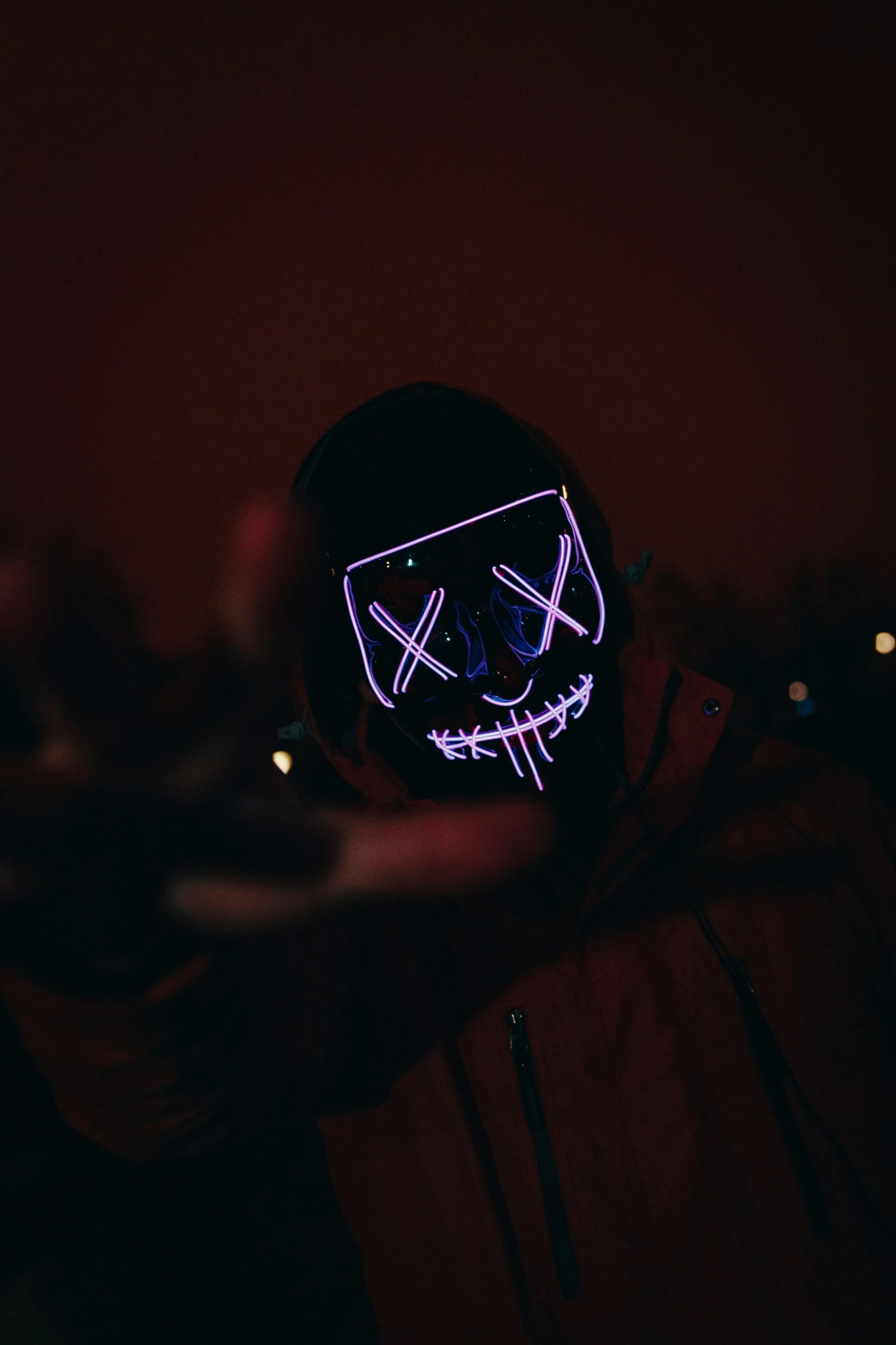 a man with a black hat has a neon mask