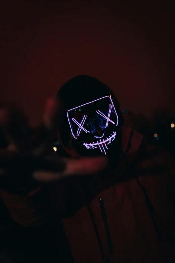 a man with a black hat has a neon mask