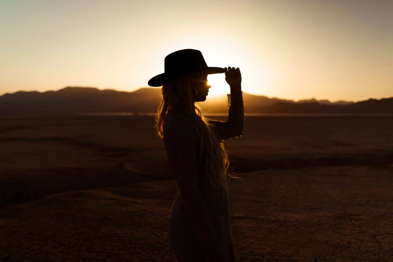 a woman with her hat covering her face in the desert