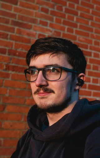 a man wearing glasses with a mustache and a hoodie