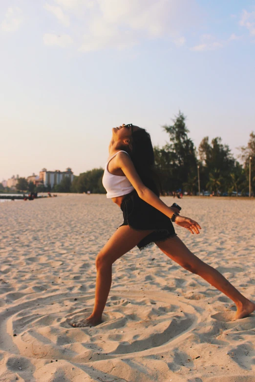 a woman stands on sand and stretches her legs