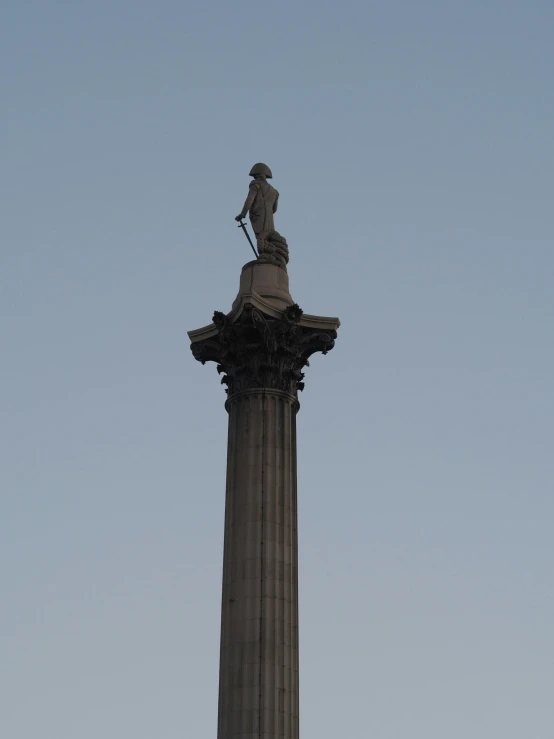 a statue stands atop a stone column in the middle of the sky