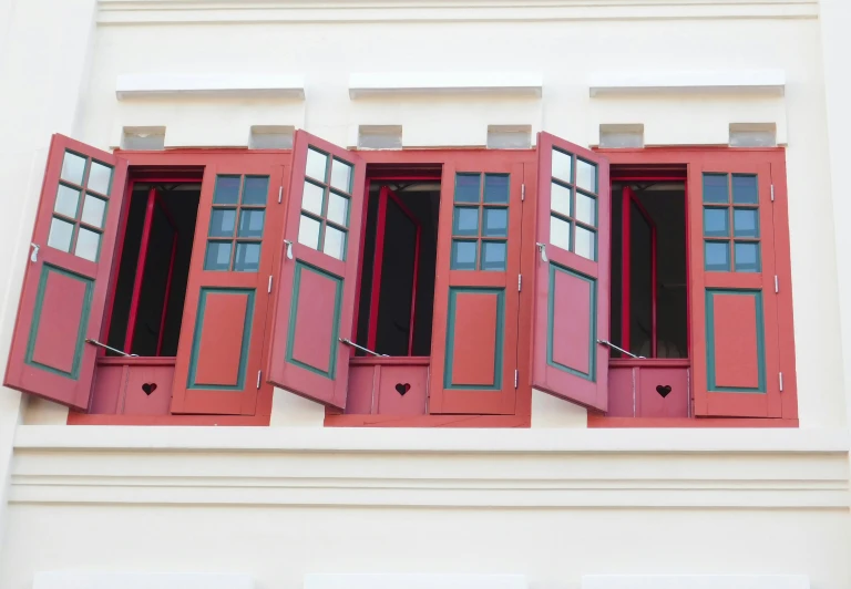 red shutters with hearts are standing in a window