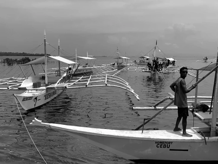 two men standing on a boat near a bunch of boats