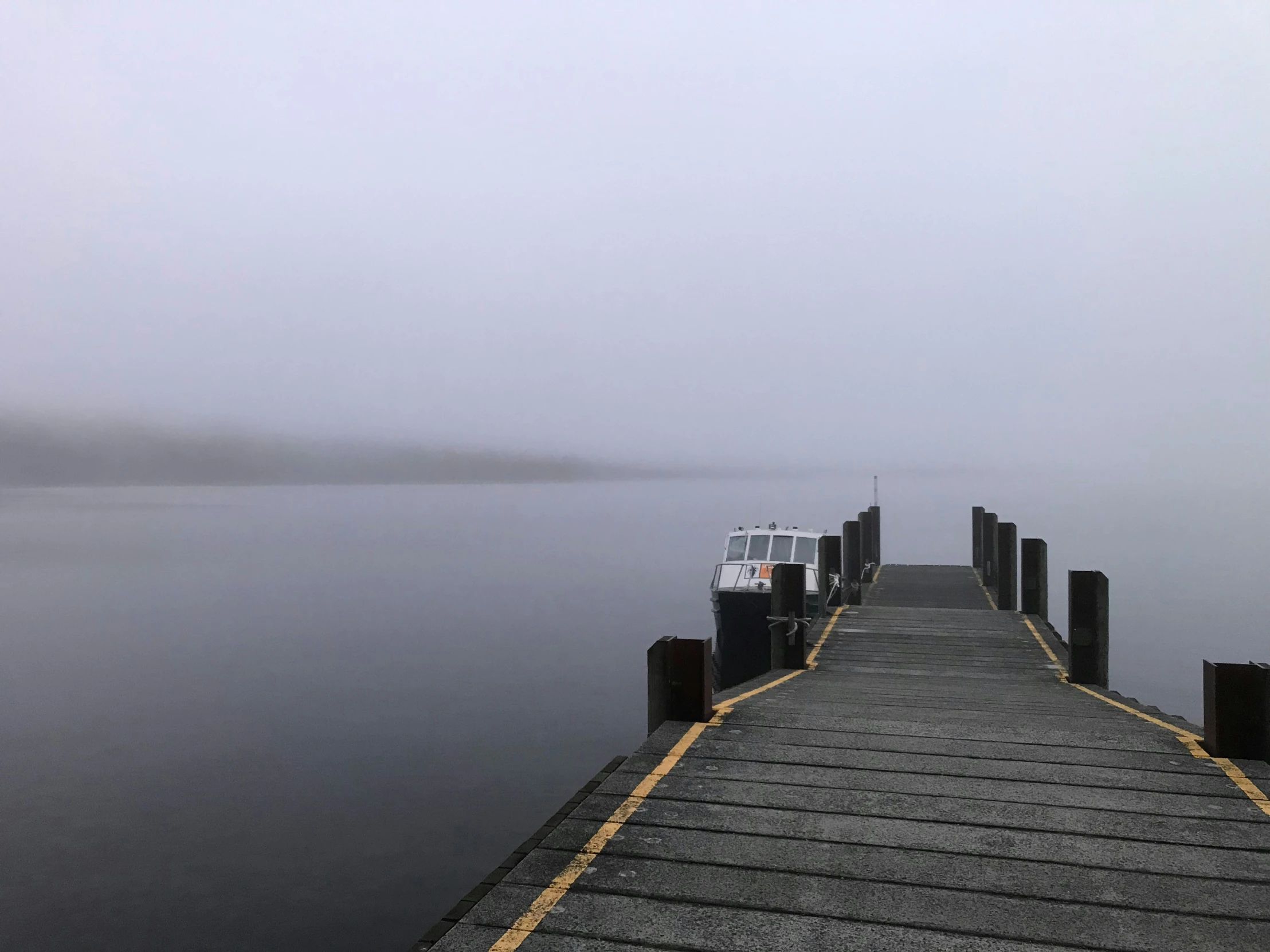a boat on the water at a dock on a foggy day