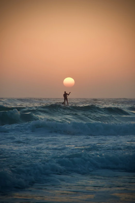 a man is surfing through the waves at sunset