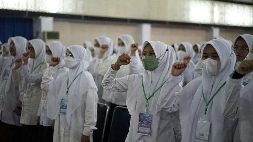 several girls are standing in a line wearing masks