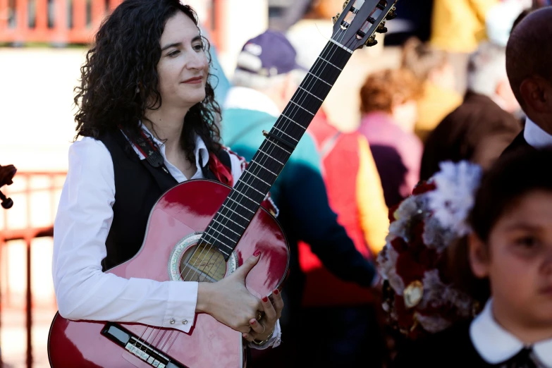 a woman playing the guitar while a man in suit and tie walks by