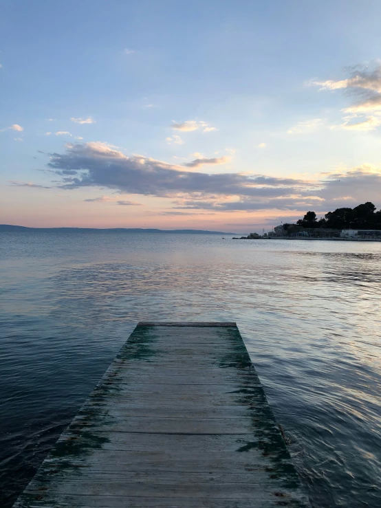 wooden dock extends into the ocean under a dramatic blue sky