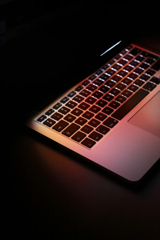 an illuminated laptop is placed on a black desk
