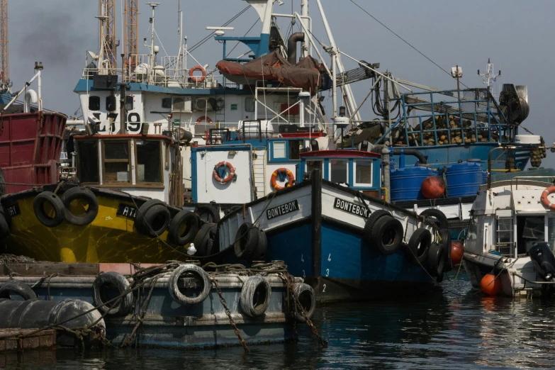 a row of tug boats sitting in a body of water