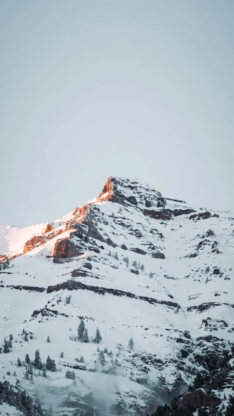 a snowy mountain with rocks below it