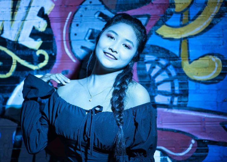 a beautiful young lady standing in front of a graffiti wall