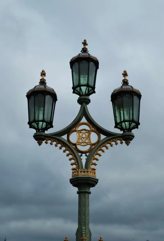 the tall light pole is standing up against the cloudy sky