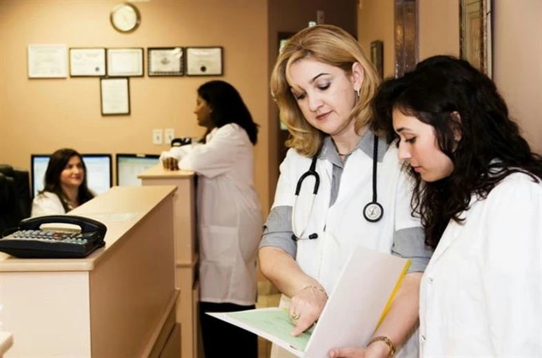 two female doctors standing at the desk, one is looking through the folder