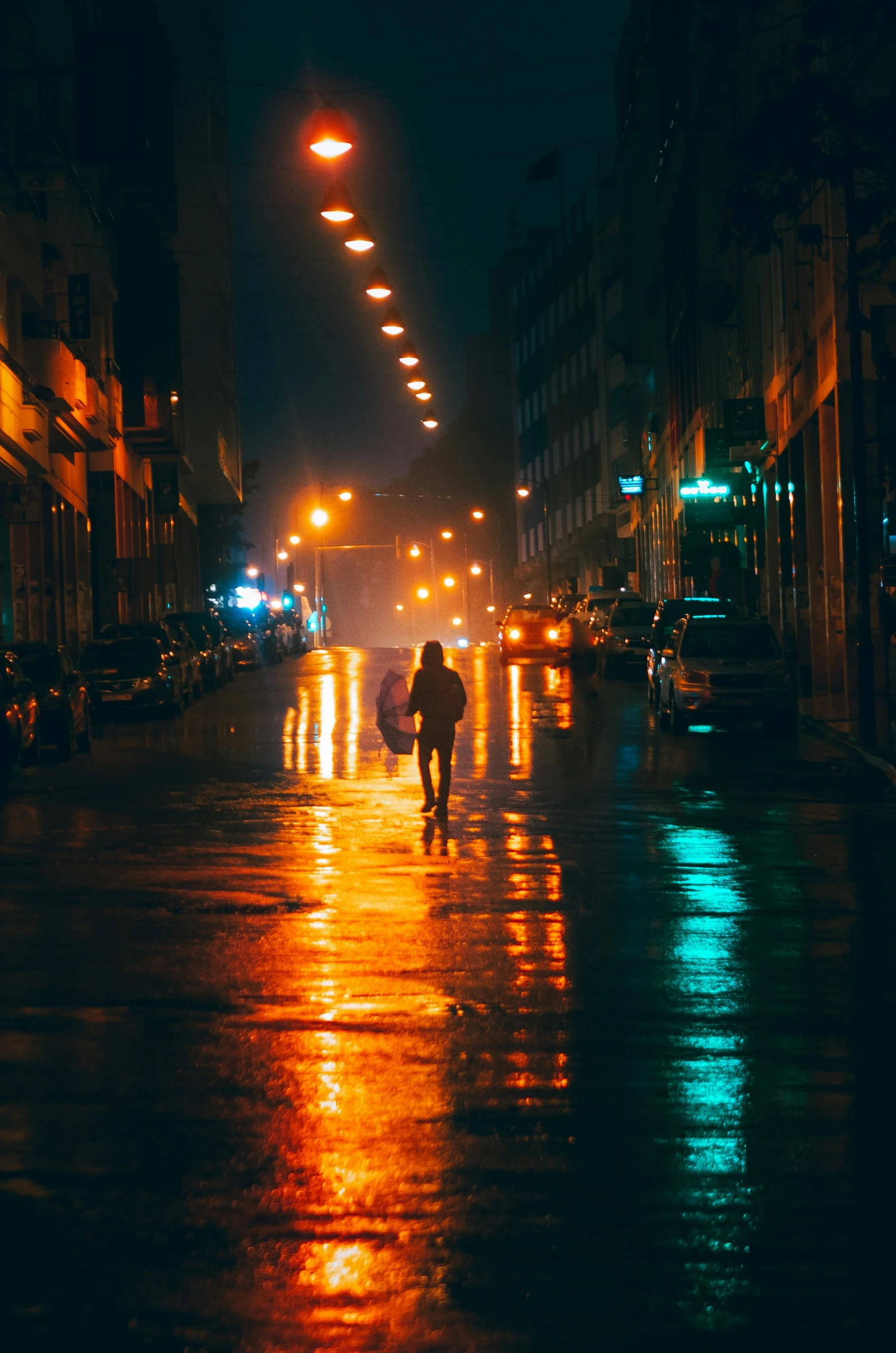 people walk along an empty street in the rain