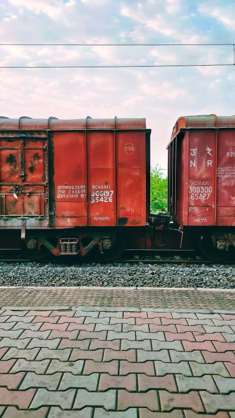 a train track with three red cargo cars on one side