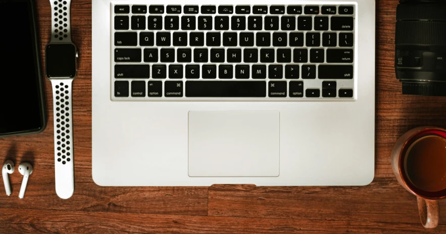 a laptop is on the table and it has a cup of coffee beside it