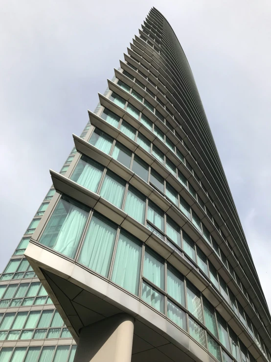 a tall building with a curved design and blue glass walls