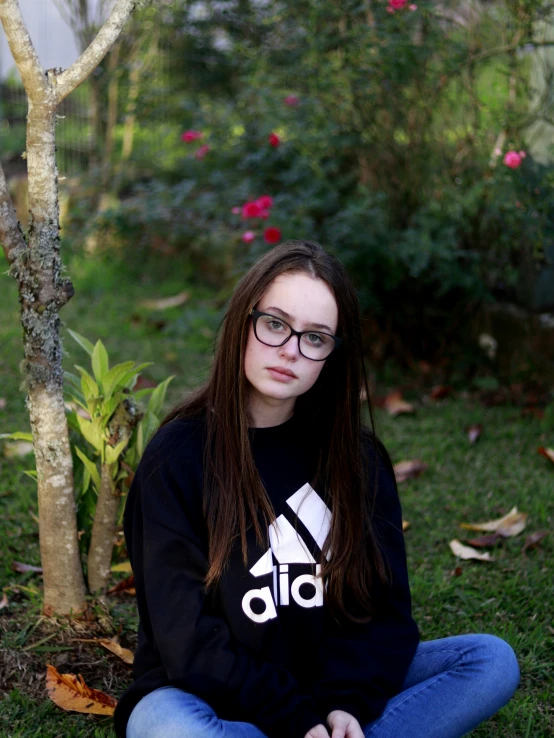 a woman with glasses sitting in front of a tree