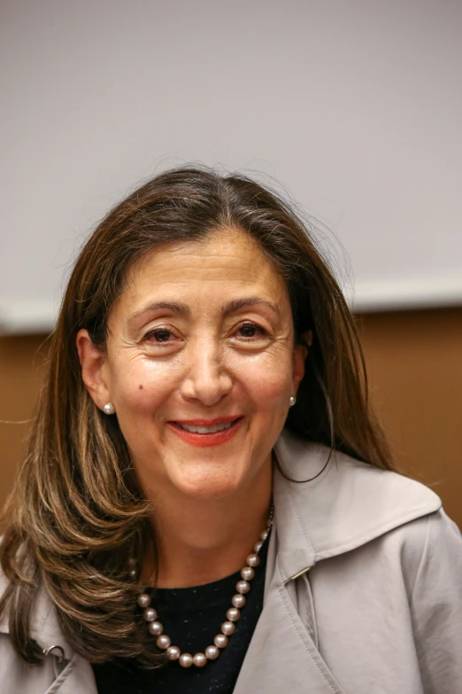 a woman wearing pearls and glasses sitting at a table