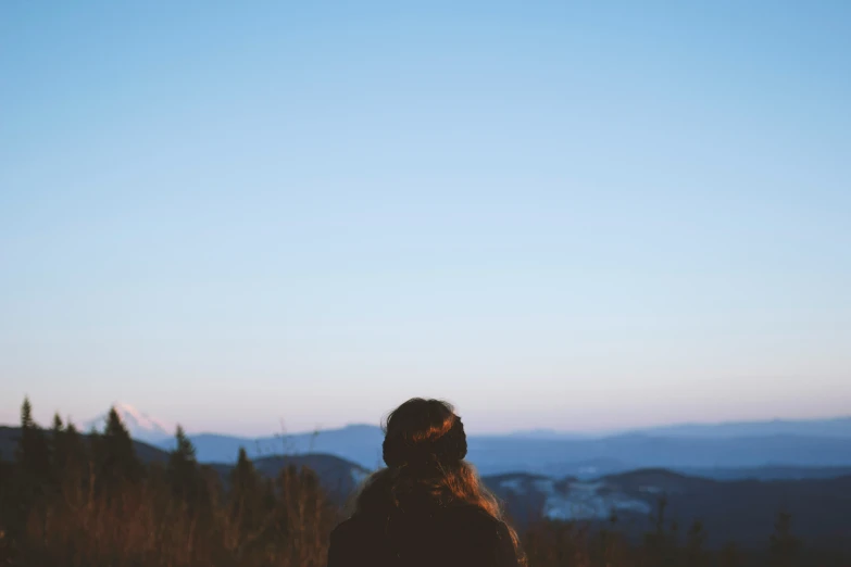 woman standing on a hillside watching a sky