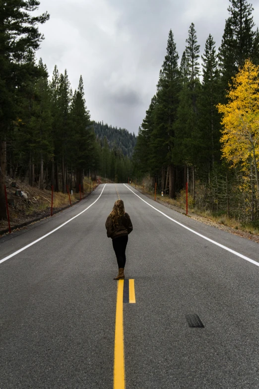 person walking down the middle of the road in the rain