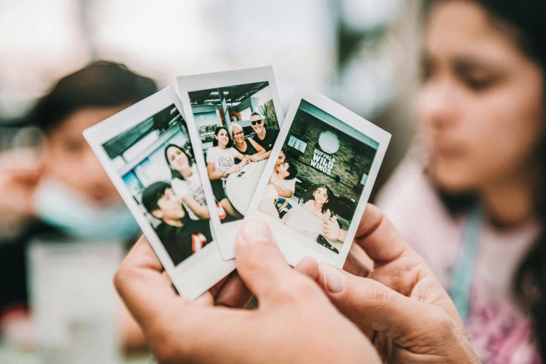 the three polaroid pos are being held up to show the people's faces