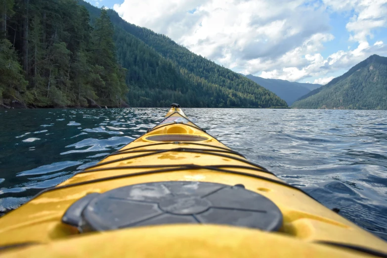 a long yellow kayak on a lake near trees
