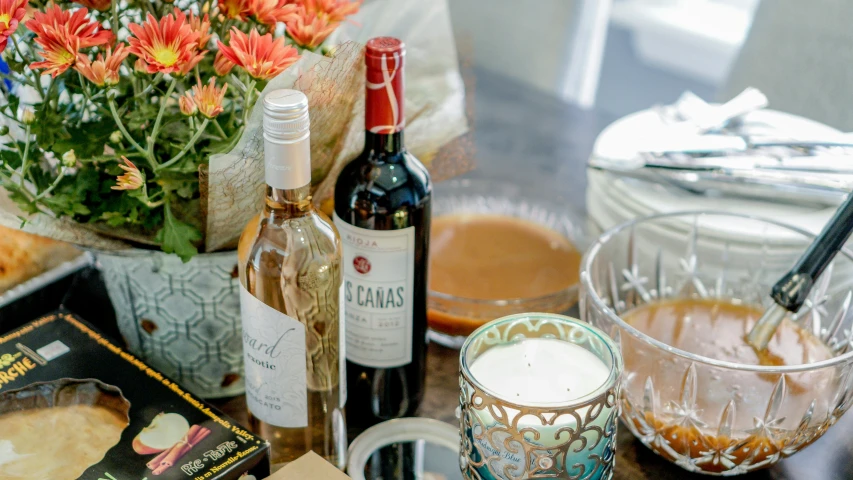 a table filled with bottles and a glass next to some orange flowers