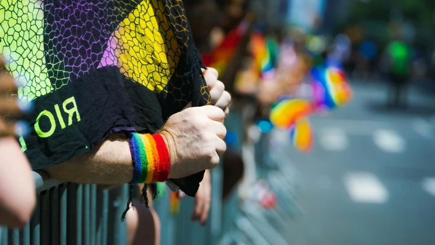 a person holding onto the arm of another person at a pride parade