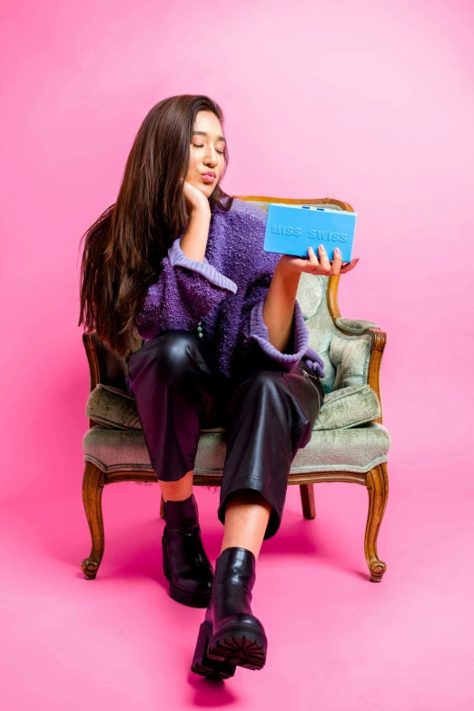 a young woman sitting in a chair holding a book