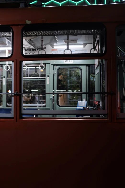 two people are seen in the reflection of the window of a subway car