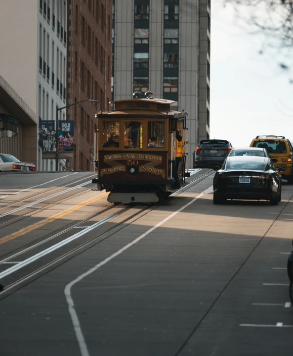 a trolly train is on a street with cars