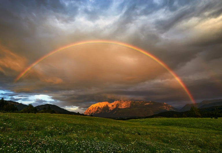 a double rainbow appears in the sky over some mountains