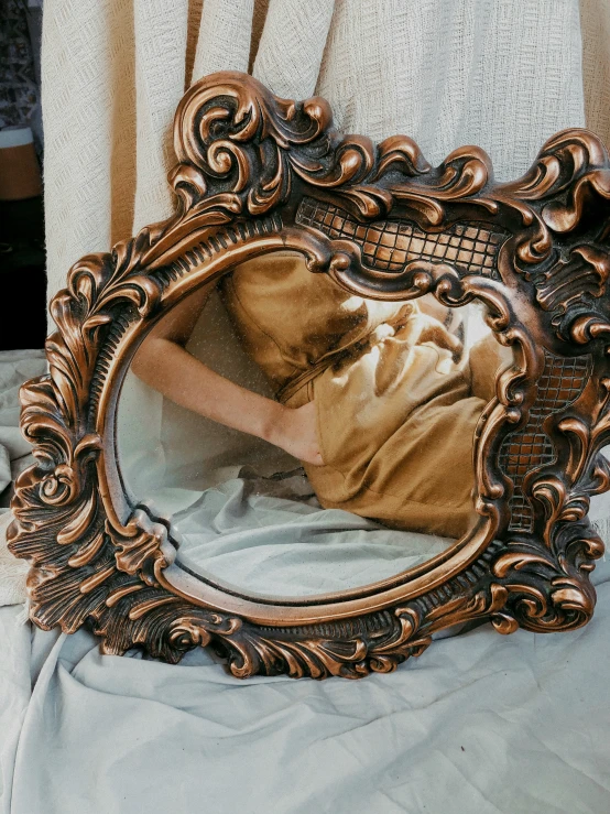 a person laying down under an ornate mirror