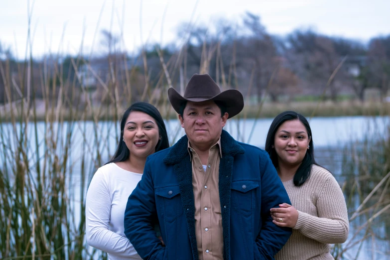 three people standing next to each other with tall grass