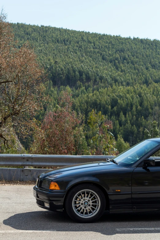 the car is parked on the road by the mountains