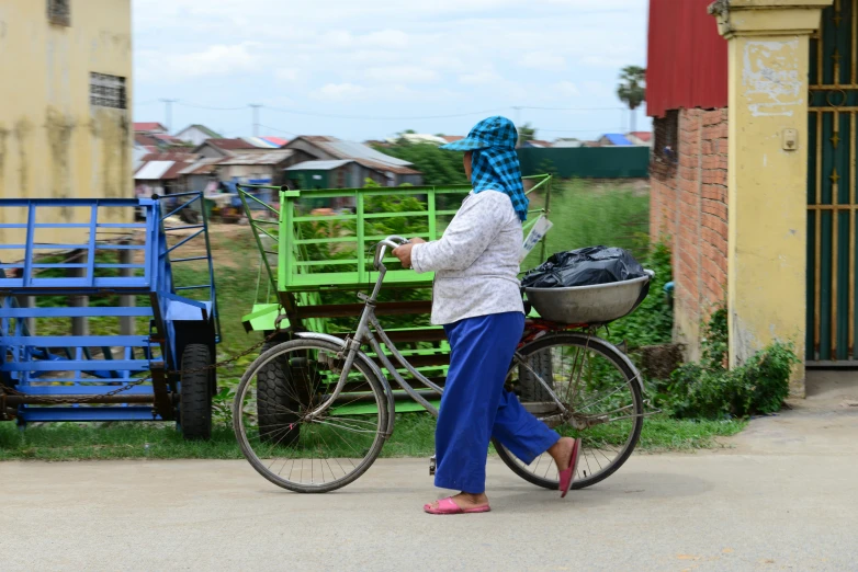 a person walking down a street with a bicycle and other items in the back