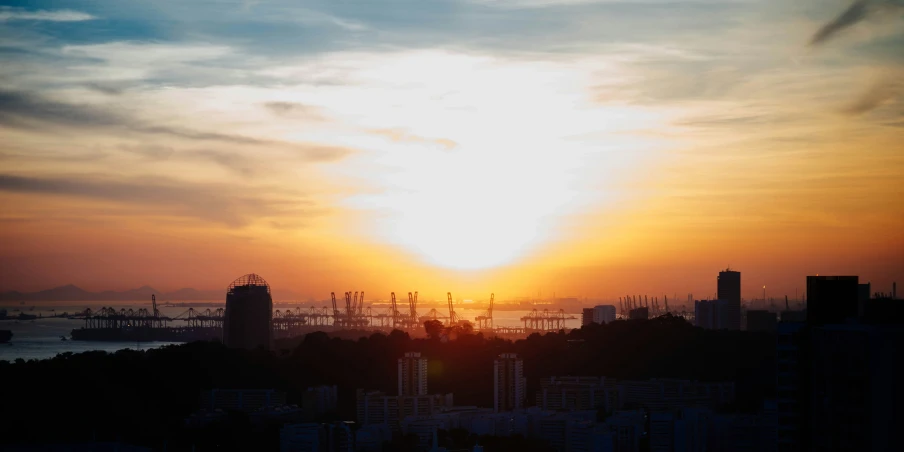 the sun sets behind tall buildings and boats in the water