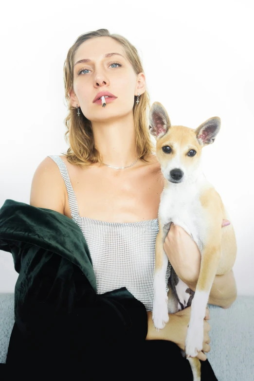 a woman is holding a small dog on a couch