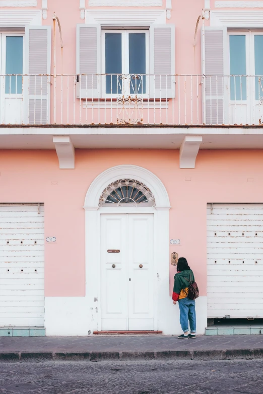 a person is standing next to a pink building