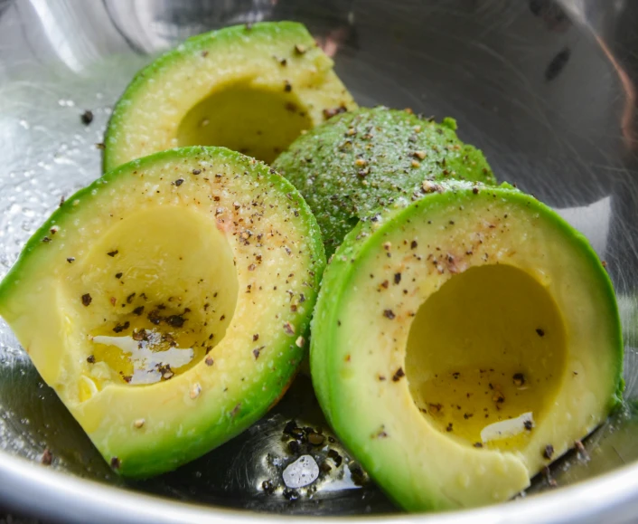 a small metal bowl full of sliced avocado slices and brown stuff